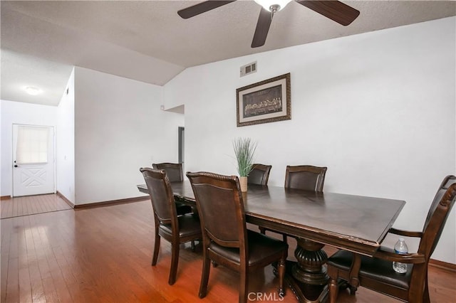 dining area featuring hardwood / wood-style floors, lofted ceiling, visible vents, and ceiling fan