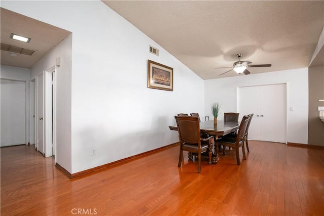 dining area featuring a ceiling fan, baseboards, visible vents, a textured ceiling, and light wood-type flooring