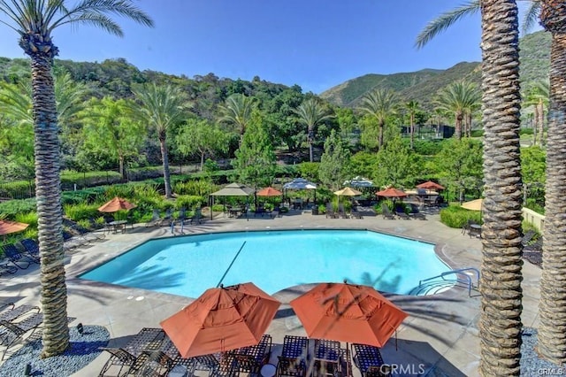 community pool with a mountain view and a patio