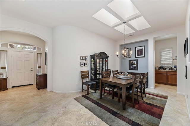 dining area with lofted ceiling with skylight, baseboards, visible vents, an inviting chandelier, and light tile patterned floors