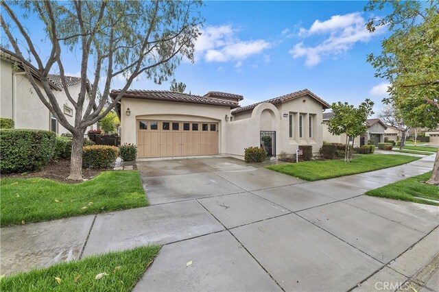 mediterranean / spanish-style home with stucco siding, concrete driveway, a front lawn, a garage, and a tile roof