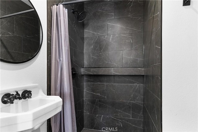 full bathroom with tiled shower and a sink