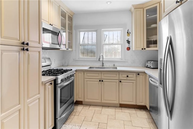 kitchen featuring a sink, appliances with stainless steel finishes, cream cabinetry, and light countertops
