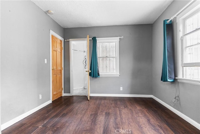unfurnished bedroom with baseboards, wood finished floors, and multiple windows