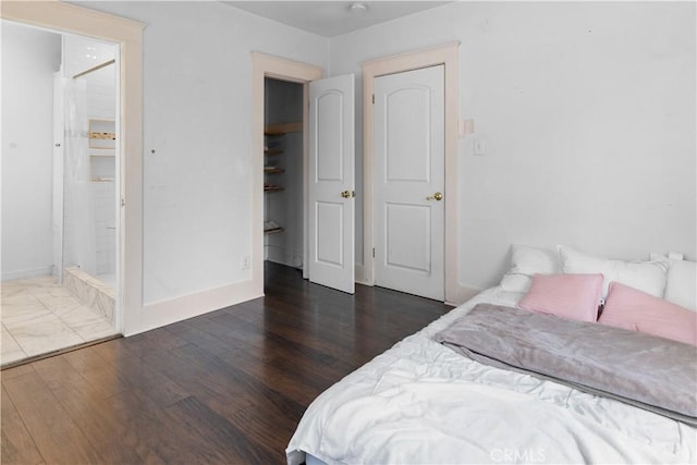 bedroom with baseboards, ensuite bathroom, and wood finished floors