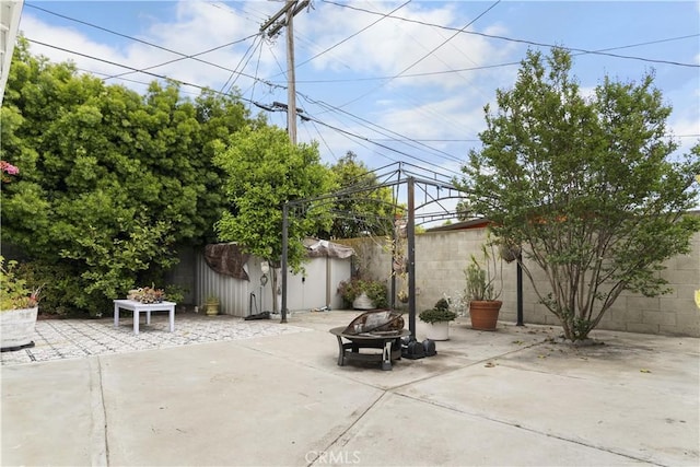 view of patio featuring an outdoor structure, a fenced backyard, and a storage unit