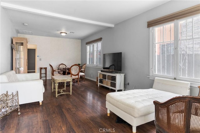 living area with baseboards, beamed ceiling, wood finished floors, and visible vents
