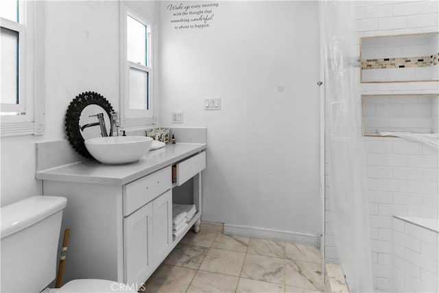 bathroom with toilet, a tile shower, marble finish floor, and vanity