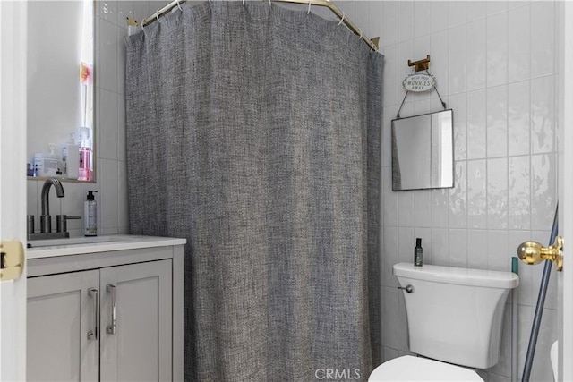 bathroom with toilet, tile walls, curtained shower, and vanity
