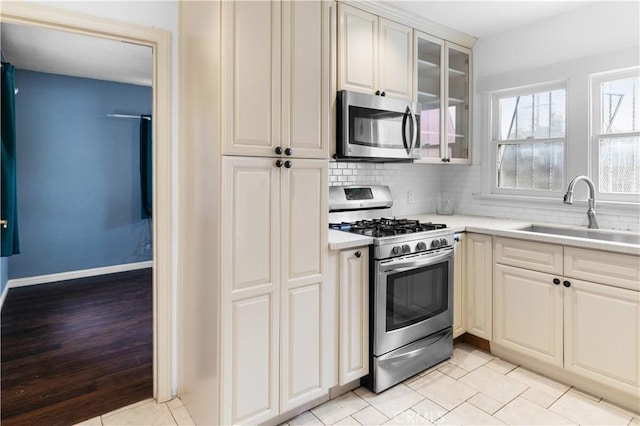kitchen with light countertops, a sink, appliances with stainless steel finishes, and tasteful backsplash