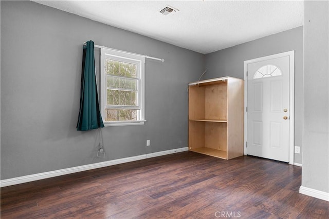 unfurnished room featuring a textured ceiling, baseboards, visible vents, and wood finished floors