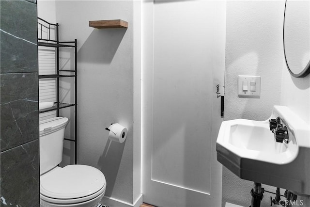 bathroom with a textured wall and toilet