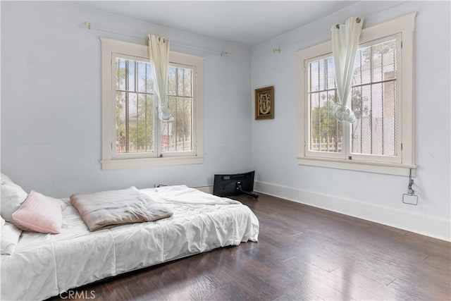 bedroom with baseboards and dark wood-type flooring