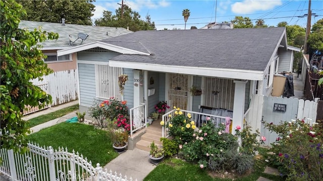 view of front facade featuring covered porch, fence private yard, and roof with shingles
