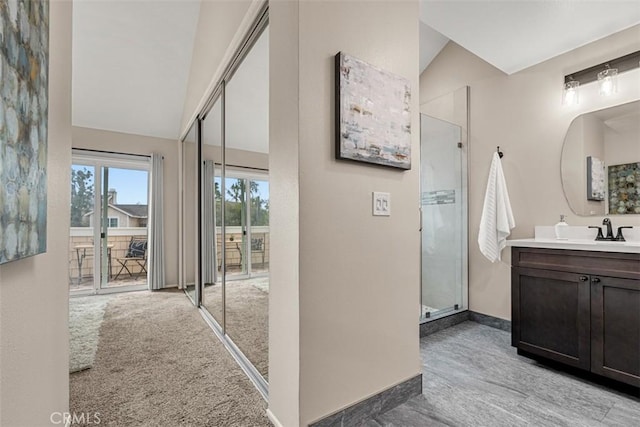 bathroom with baseboards, a stall shower, vanity, and vaulted ceiling