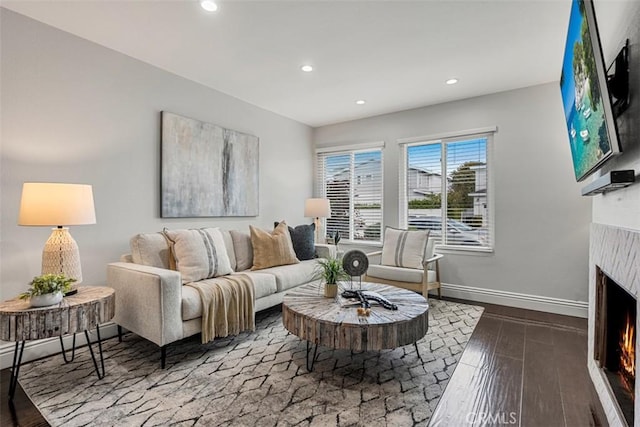 living area featuring hardwood / wood-style flooring, recessed lighting, baseboards, and a lit fireplace