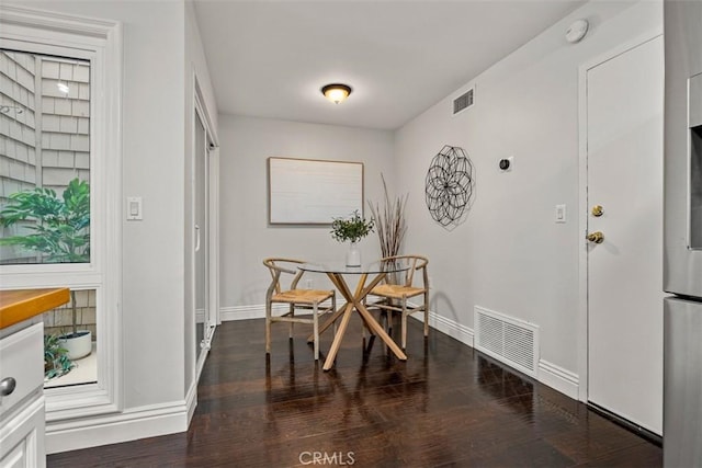 dining room with wood finished floors, visible vents, and baseboards