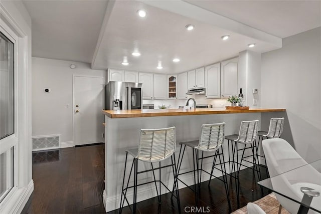 kitchen featuring visible vents, stainless steel fridge, a peninsula, wooden counters, and dark wood-style flooring