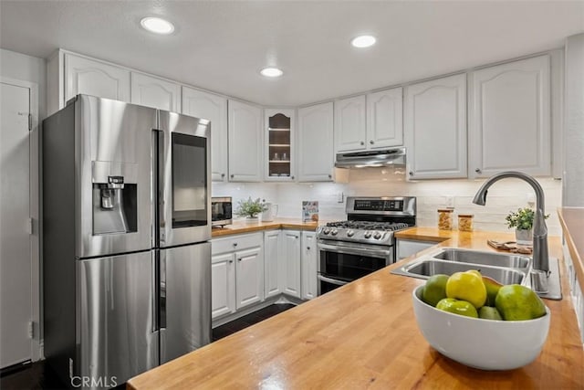 kitchen featuring a sink, butcher block countertops, stainless steel appliances, white cabinets, and under cabinet range hood