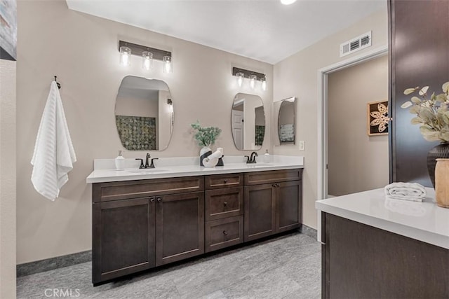 bathroom with double vanity, baseboards, visible vents, and a sink