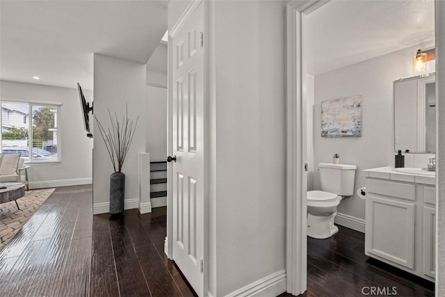 bathroom with baseboards, toilet, recessed lighting, hardwood / wood-style flooring, and vanity