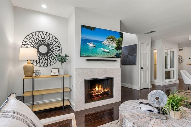 living area with wood finished floors, visible vents, baseboards, recessed lighting, and a tiled fireplace