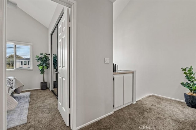 corridor with baseboards, carpet floors, and lofted ceiling