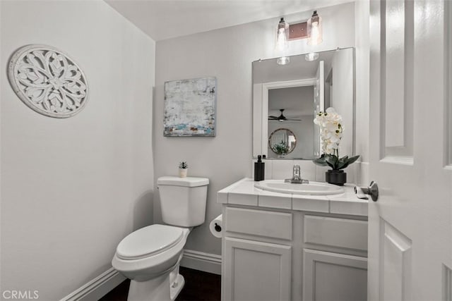 bathroom featuring vanity, toilet, a ceiling fan, and baseboards