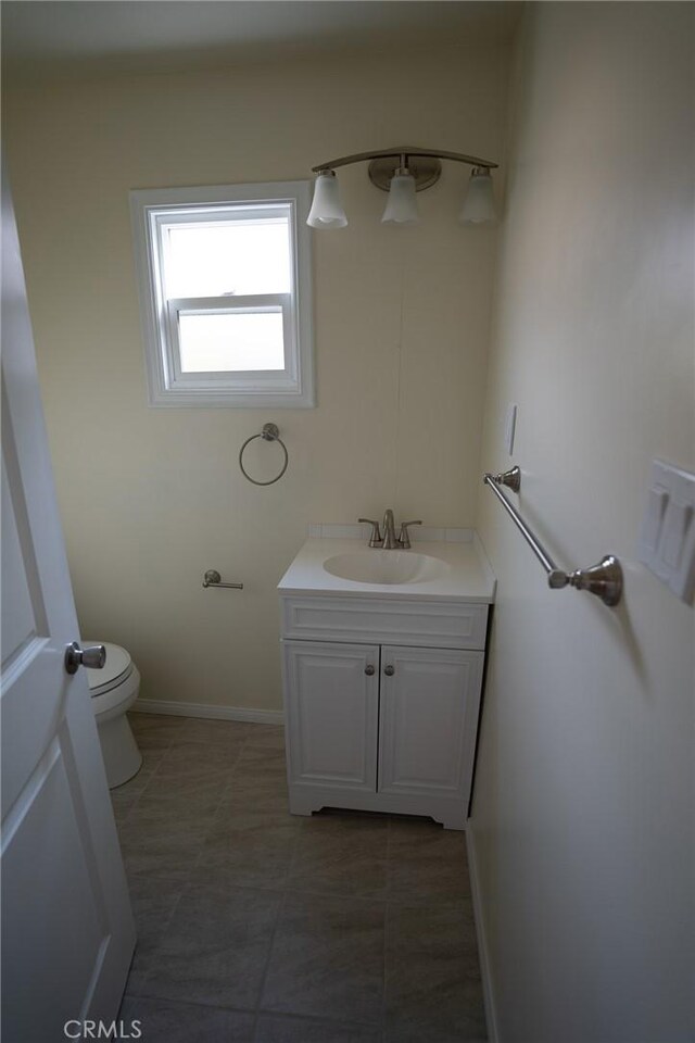 bathroom with baseboards, toilet, vanity, and tile patterned flooring