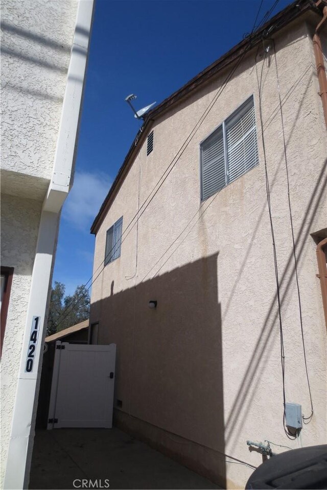 view of side of home with a gate and stucco siding