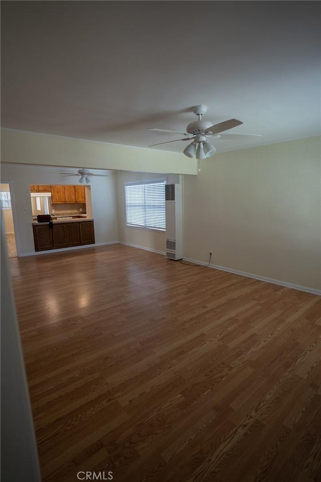 interior space featuring baseboards, a ceiling fan, and wood finished floors