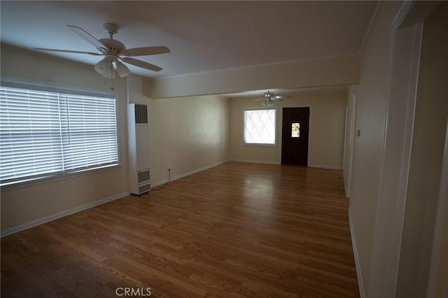 spare room with baseboards, wood finished floors, a ceiling fan, and ornamental molding