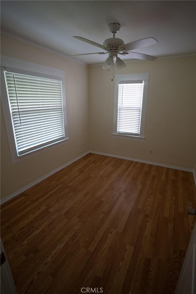 spare room featuring baseboards, crown molding, a ceiling fan, and wood finished floors