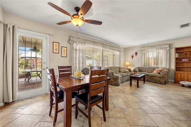 dining room featuring a textured ceiling, a ceiling fan, visible vents, and stone finish flooring