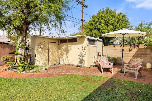 view of yard featuring an outdoor structure, a fenced backyard, and a patio