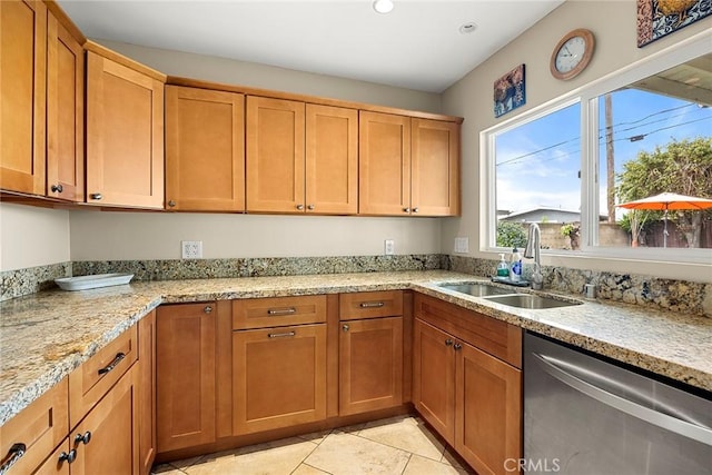 kitchen featuring stainless steel dishwasher, light stone counters, light tile patterned floors, and a sink