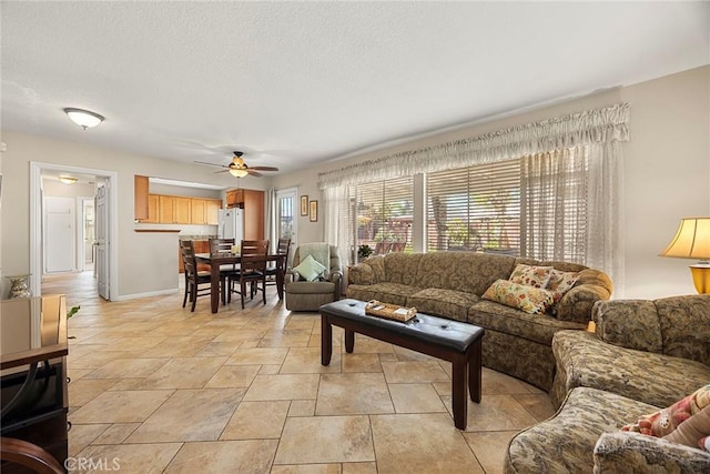 living area featuring baseboards, a textured ceiling, and ceiling fan