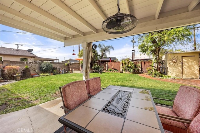 view of patio / terrace featuring an outbuilding, outdoor dining area, and a fenced backyard