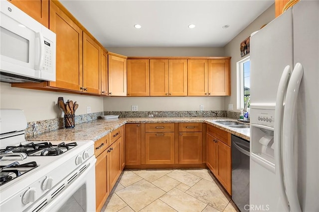 kitchen featuring recessed lighting, white appliances, light stone countertops, and a sink