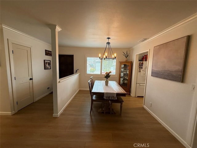 dining space with visible vents, wood finished floors, an inviting chandelier, crown molding, and baseboards