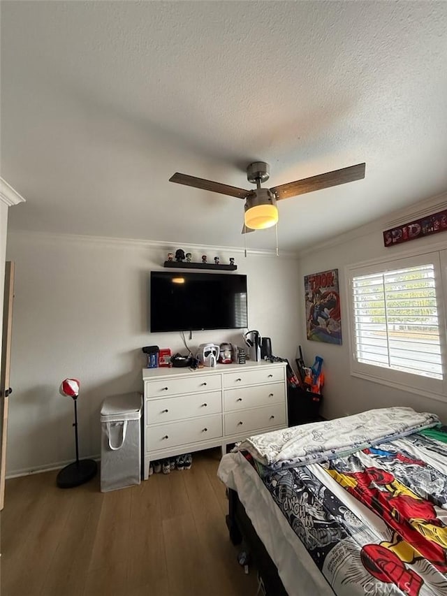 bedroom featuring ornamental molding, a textured ceiling, ceiling fan, and wood finished floors