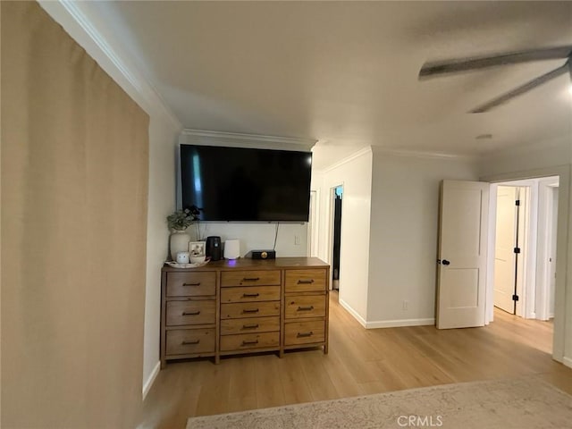 interior space featuring baseboards, light wood-style floors, ornamental molding, and a ceiling fan