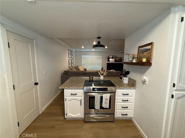 kitchen featuring a peninsula, stainless steel range with electric stovetop, baseboards, and white cabinets