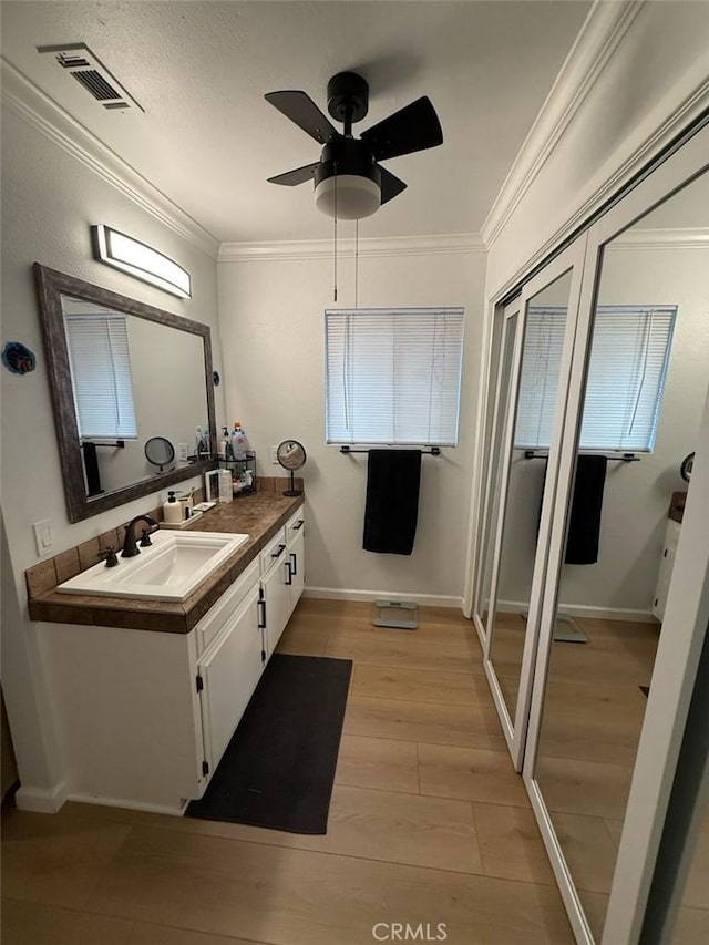 bathroom featuring visible vents, crown molding, ceiling fan, and wood finished floors