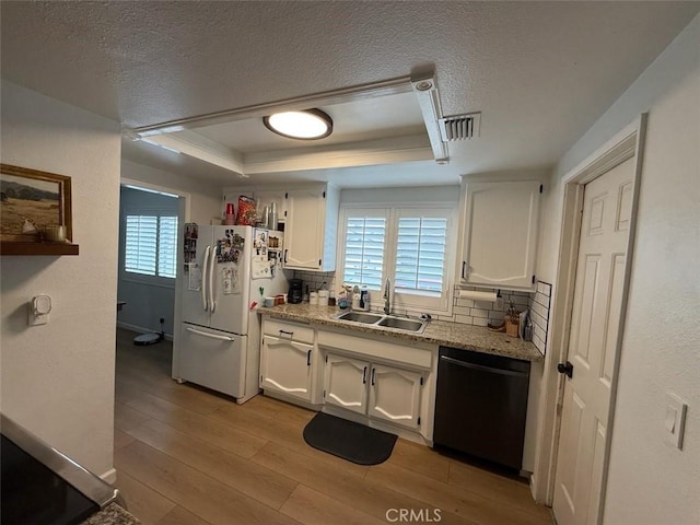 kitchen featuring black dishwasher, freestanding refrigerator, white cabinetry, a raised ceiling, and a sink