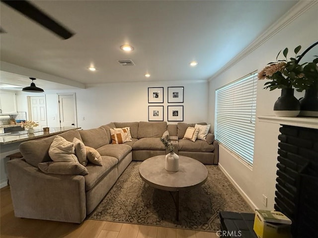 living area featuring visible vents, crown molding, baseboards, recessed lighting, and wood finished floors