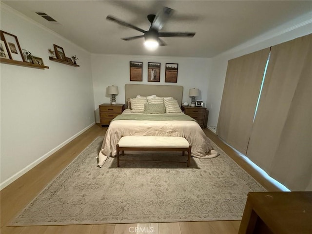 bedroom featuring visible vents, ornamental molding, wood finished floors, baseboards, and ceiling fan