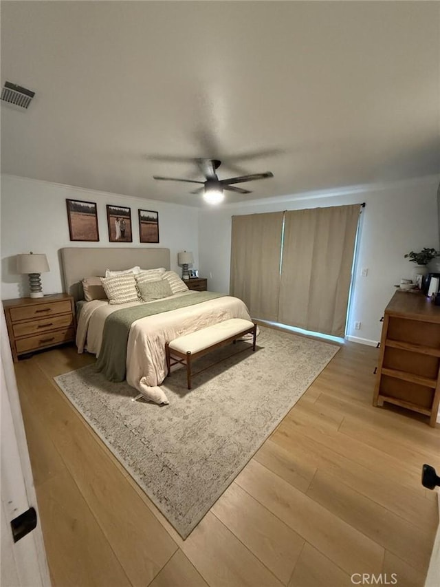 bedroom with light wood-type flooring, visible vents, and ceiling fan