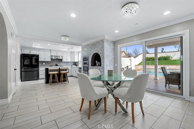 dining room with baseboards, wood tiled floor, recessed lighting, crown molding, and a notable chandelier