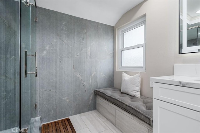 bathroom with a tile shower, vanity, and vaulted ceiling